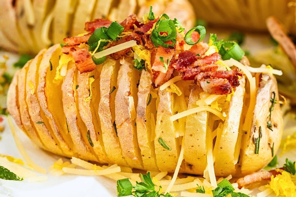 Sliced baked potato topped with bacon, cheese, and green onions.
