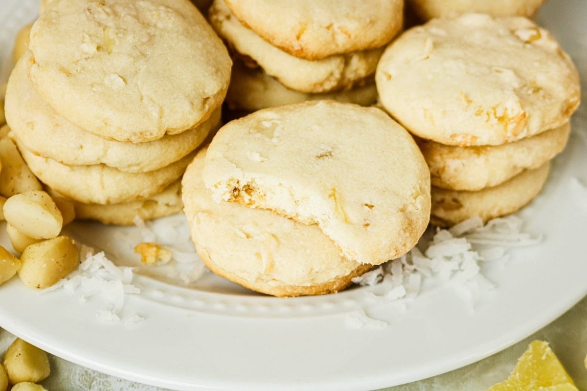 Stacked coconut cookies on a plate, one with a bite taken out.