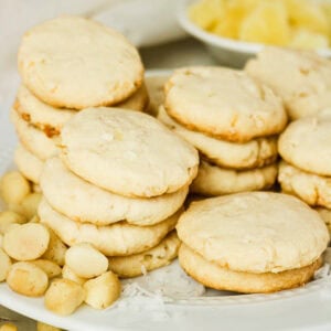 Stacks of shortbread cookies with macadamia nuts and coconut on a white plate.