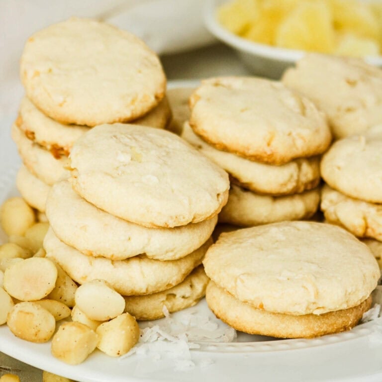 Stacks of shortbread cookies with macadamia nuts and coconut on a white plate.