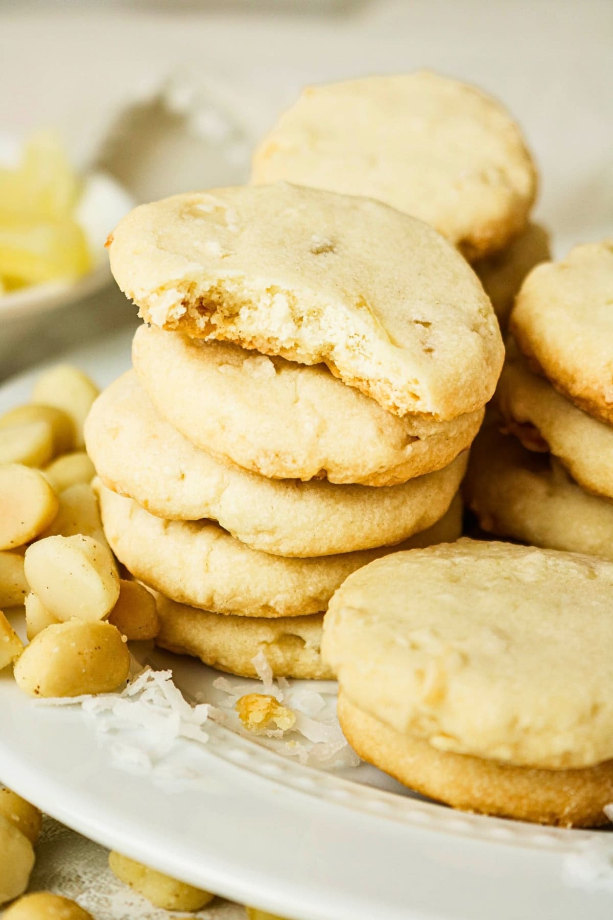 A stack of cookies with macadamia nuts, one cookie has a bite taken out.