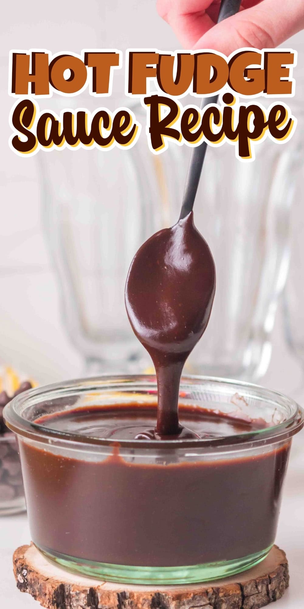 A spoon lifts hot fudge sauce from a glass bowl.
