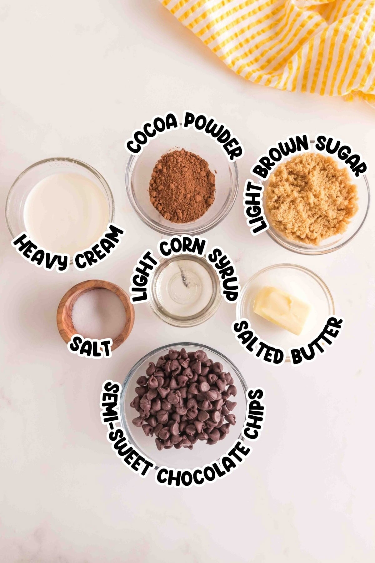 Seven labeled bowls with chocolate chips, cocoa, brown sugar, cream, corn syrup, butter, and salt.