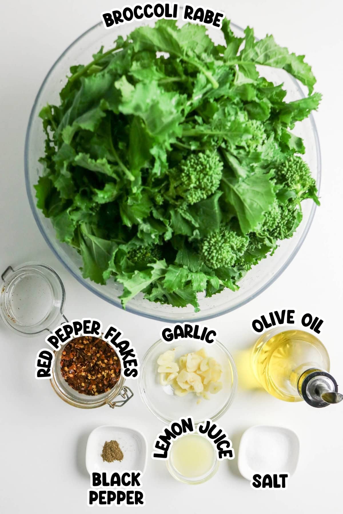Bowl of broccoli rabe with small bowls of spices, oil, lemon juice, and garlic.