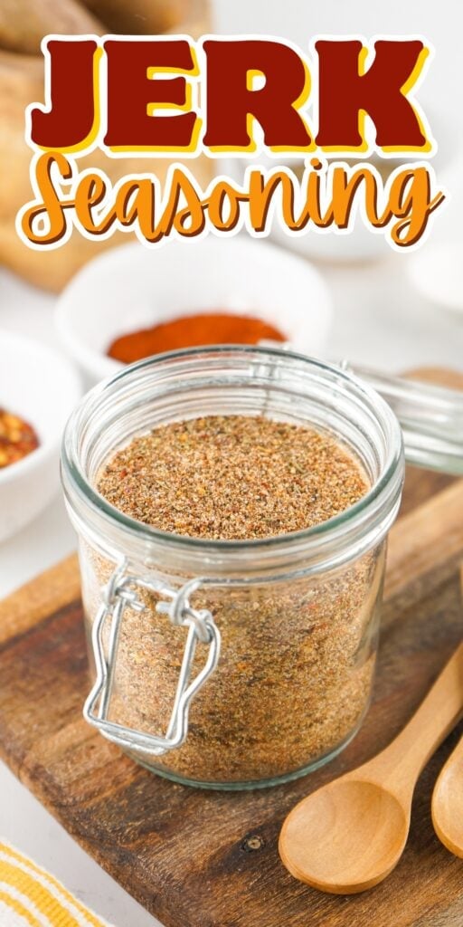 A jar of jerk seasoning on a wooden board with spoons and bowls nearby.