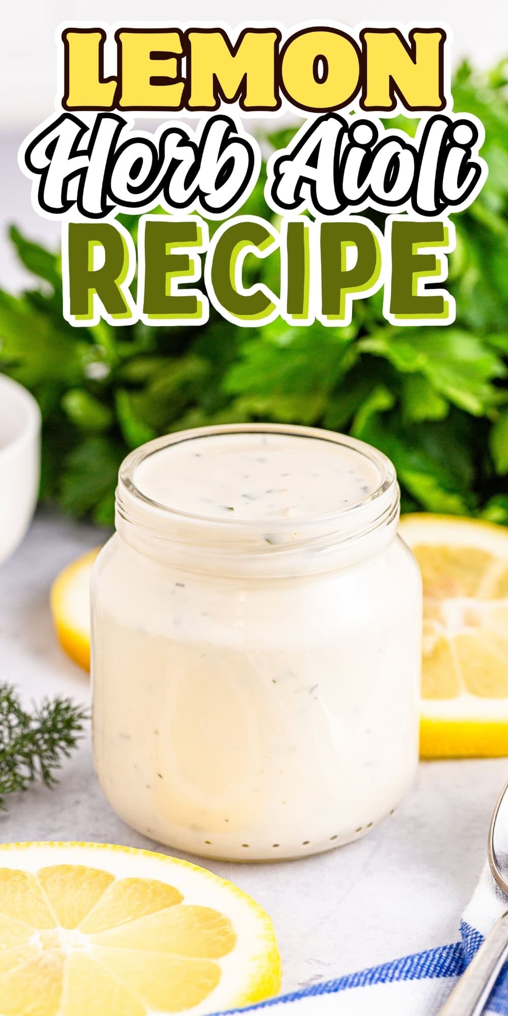 Jar of lemon herb aioli with lemon slices and herbs beside it.