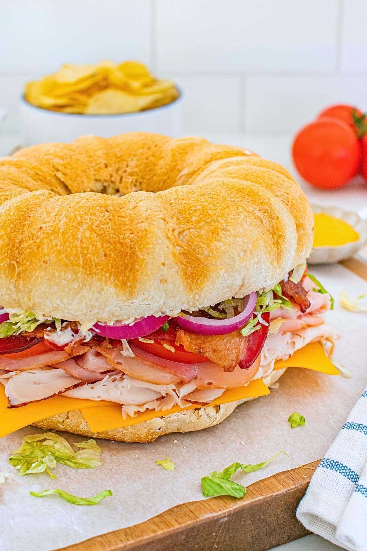 A large round sandwich with deli meats, cheese, lettuce, tomato, and onion.