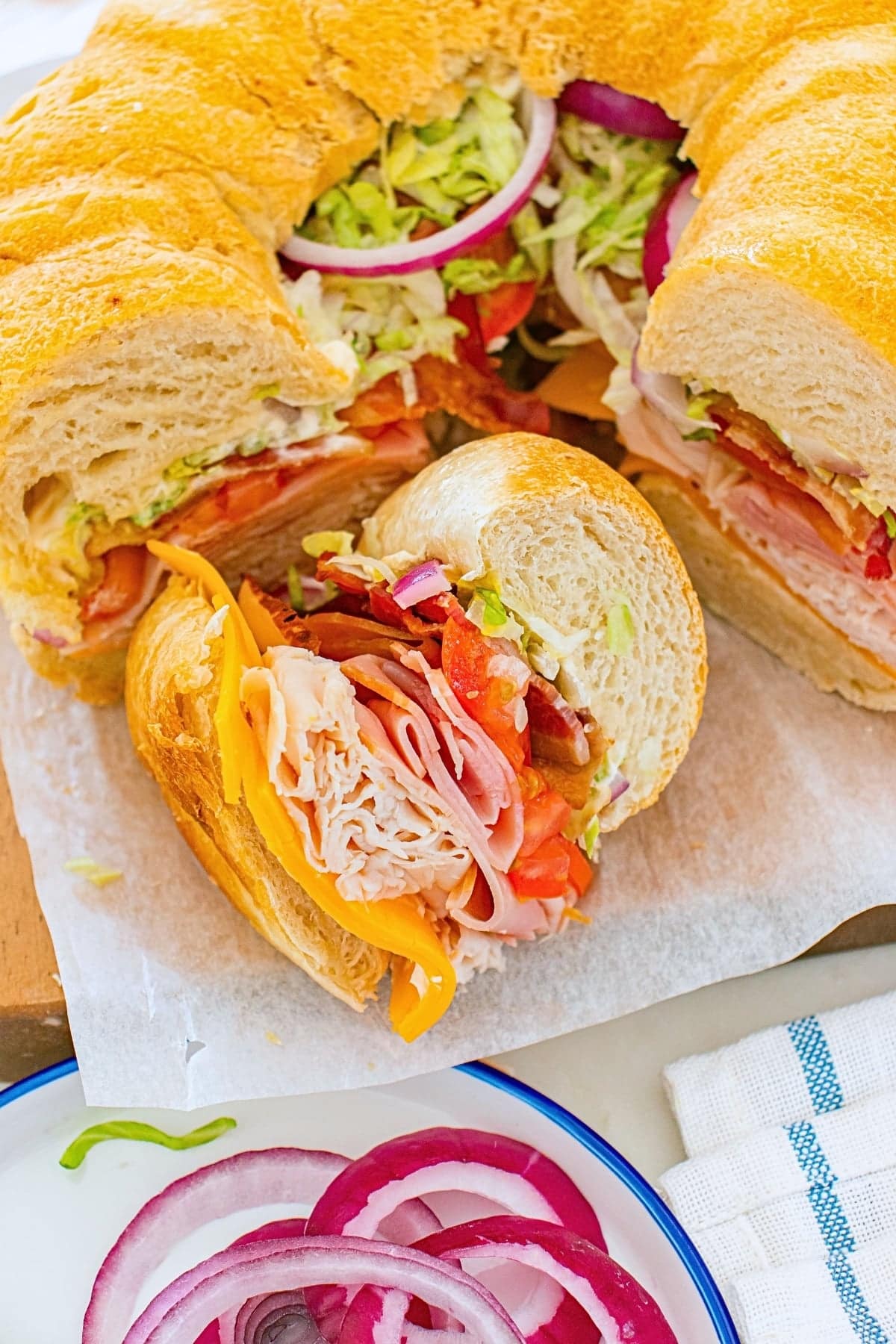 Sandwich ring with turkey, ham, cheese, lettuce, tomato, and onions.