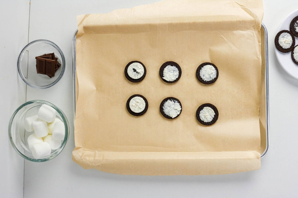 Oreos split with filling on a tray; chocolate and marshmallows are nearby.