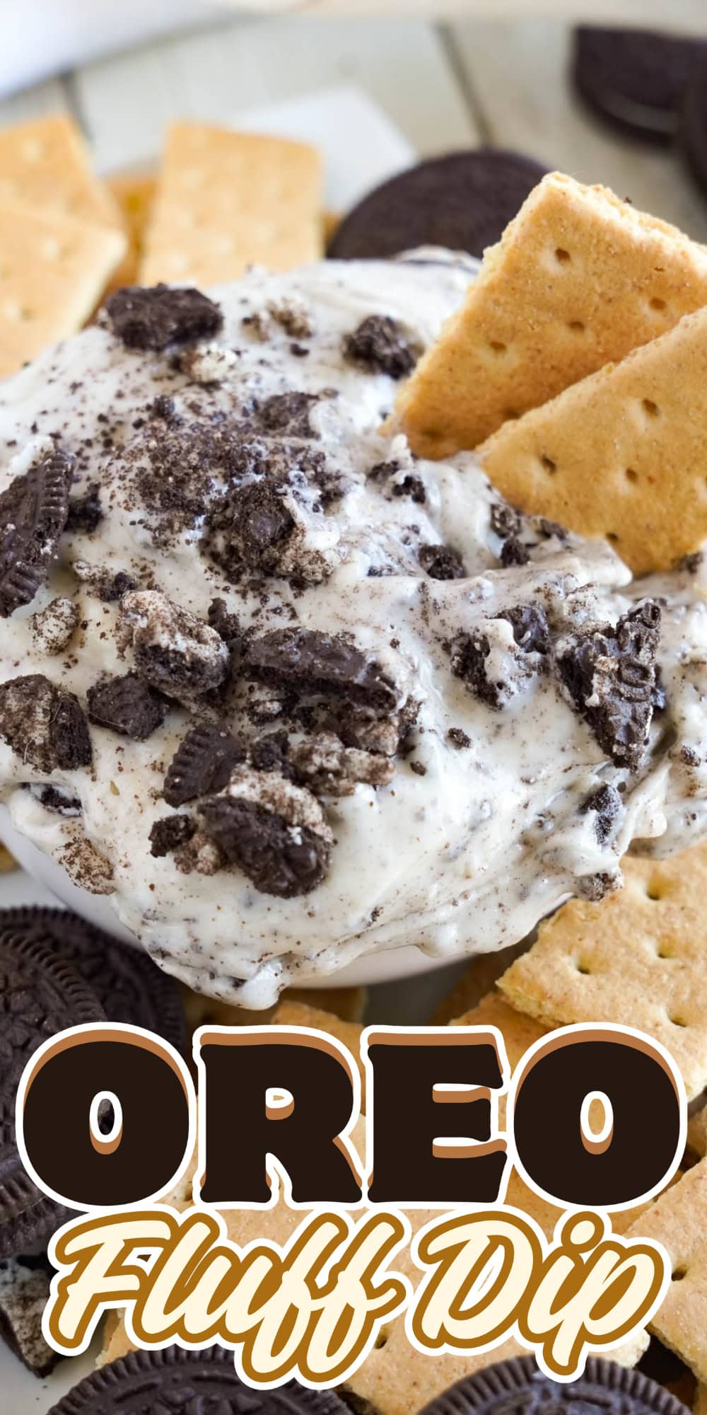 Bowl of Oreo fluff dip with crushed Oreos and graham crackers around it.
