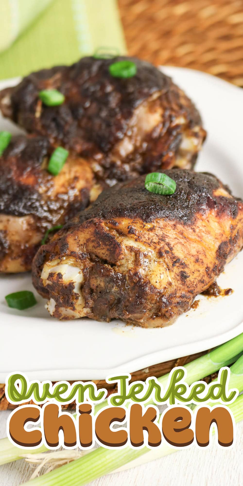 Three pieces of oven jerked chicken garnished with green onions on a white plate.