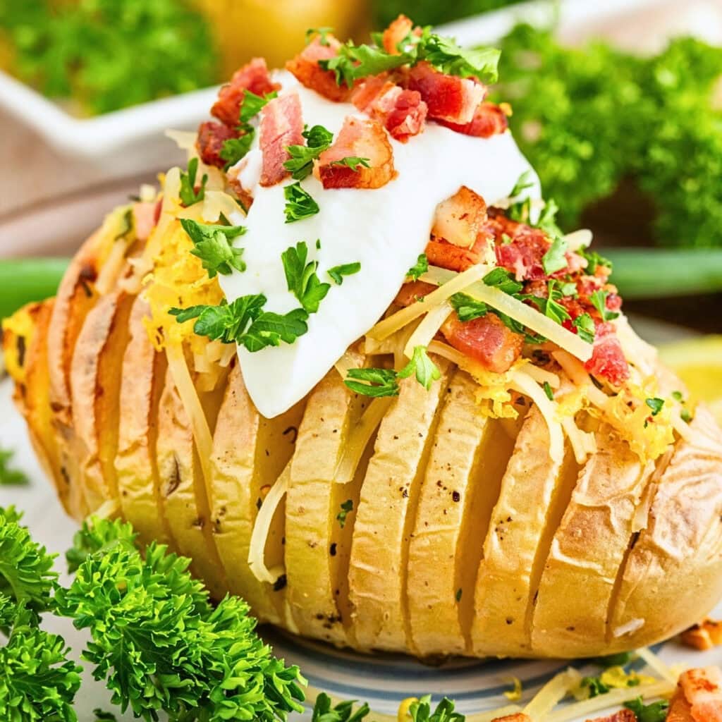 Sliced baked potato with cheese, bacon, sour cream, and parsley on top.