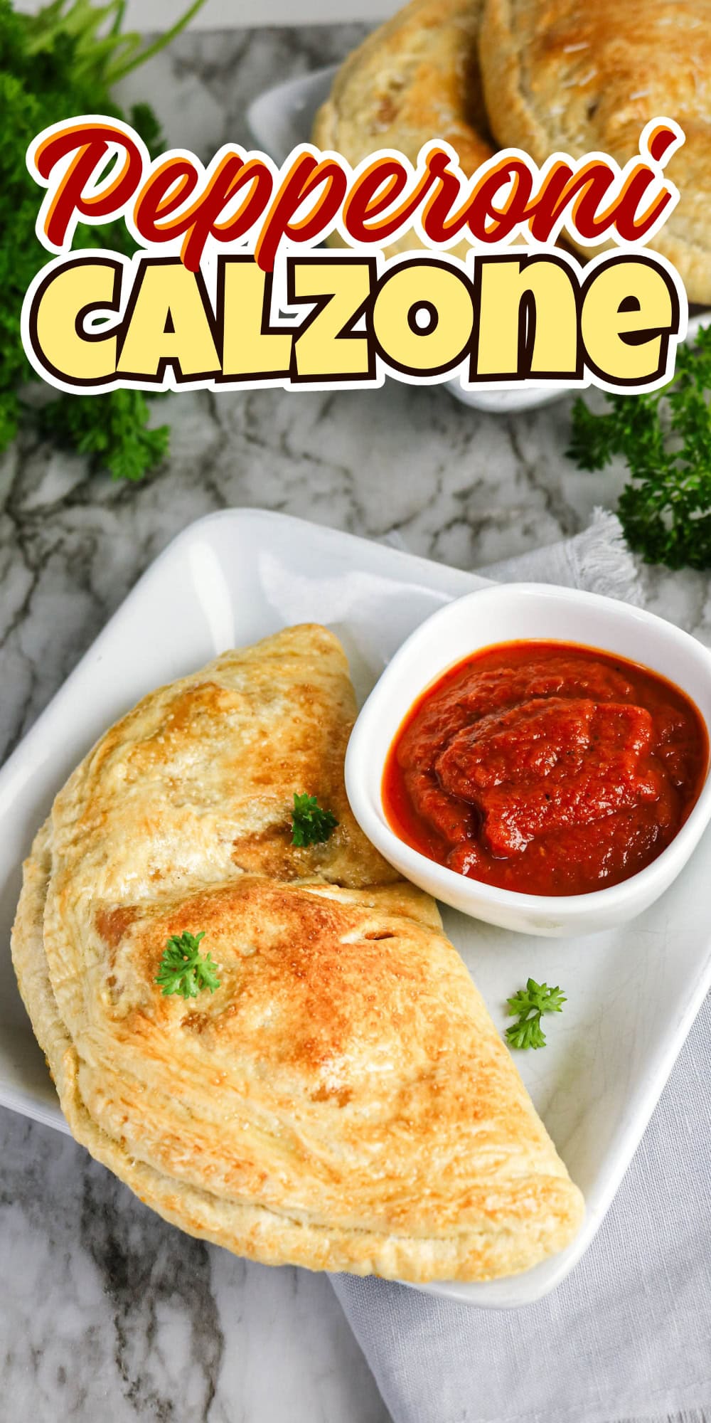 A pepperoni calzone on a plate with marinara dipping sauce.