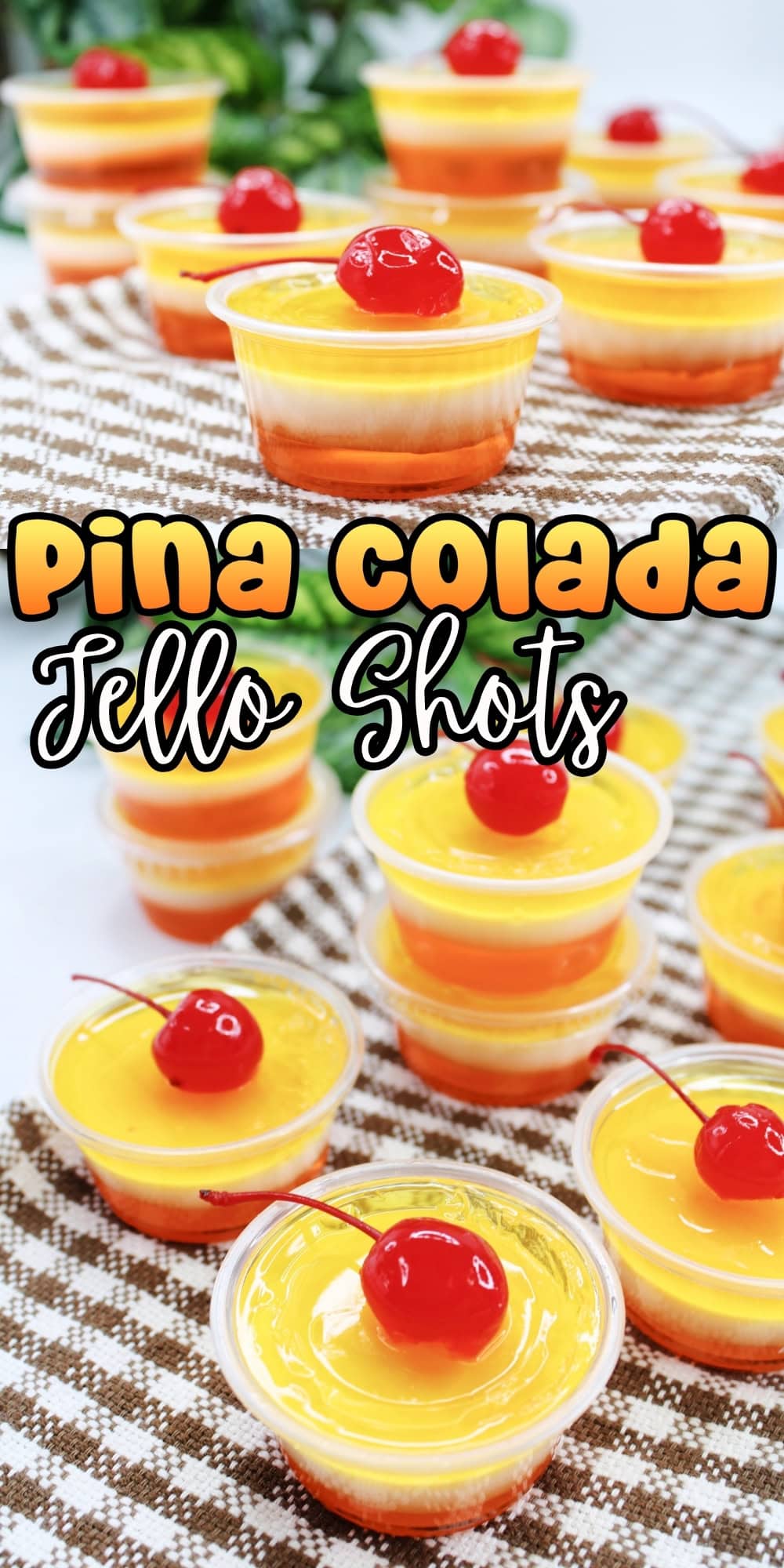Small yellow jello shots in cups, each topped with a red cherry.