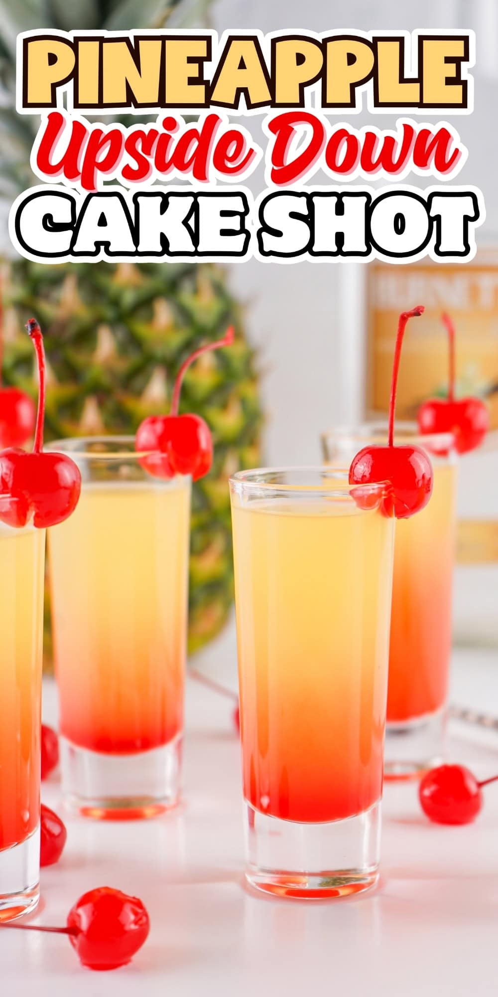 Four pineapple upside down cake shots with cherries, pineapple in background.