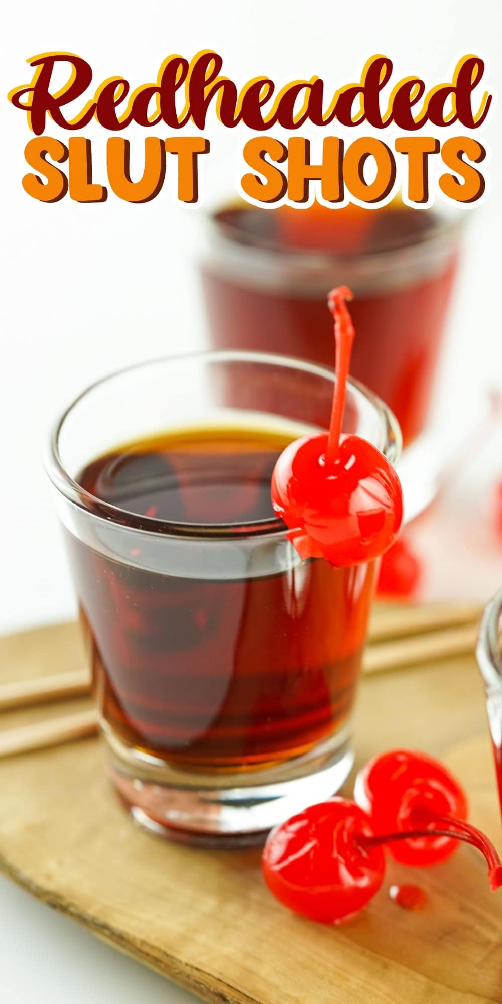 Shot glass with red liquid and cherry.