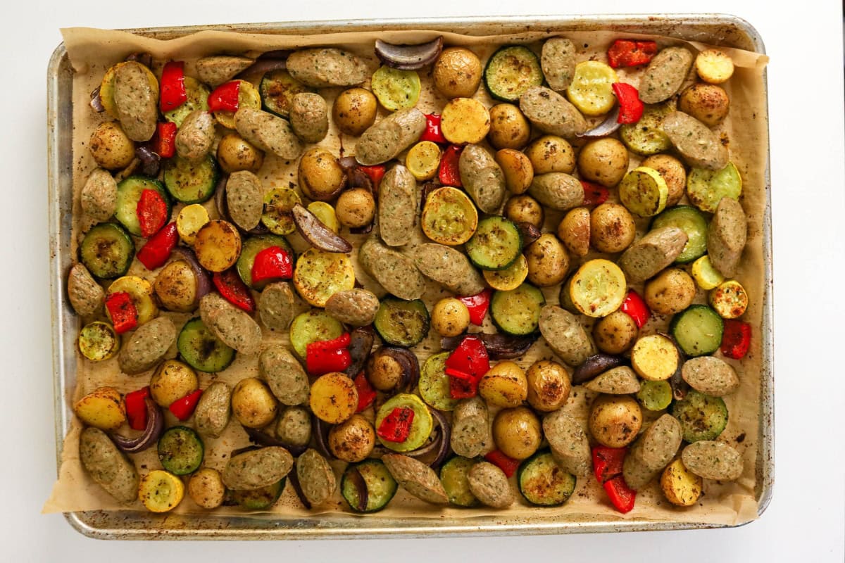 Sheet pan with roasted potatoes, zucchini, red peppers, onions, and sausage.