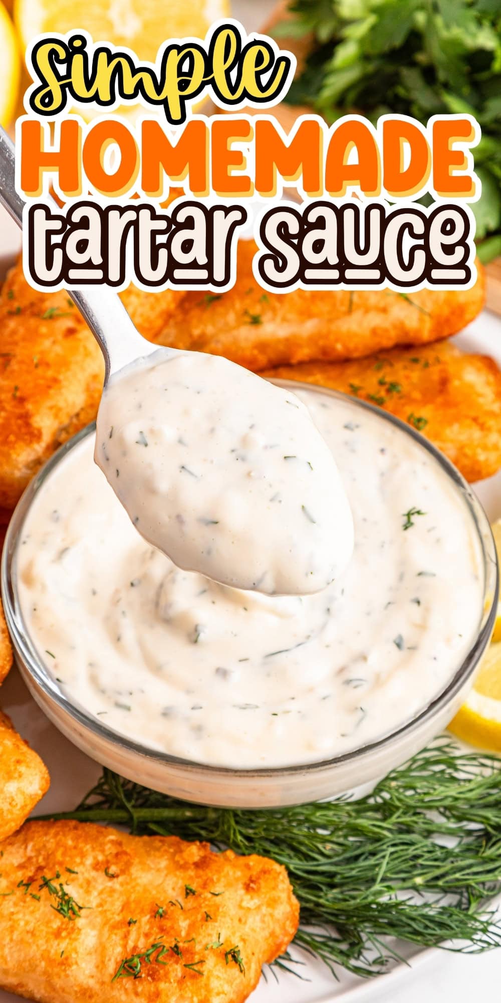 A spoonful of tartar sauce above a bowl, with fish sticks and herbs nearby.
