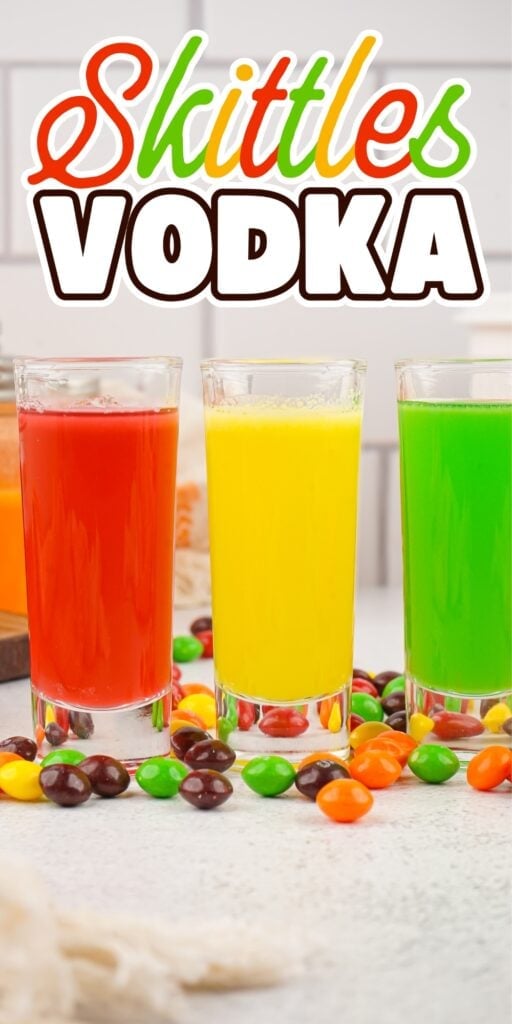 Three colorful Skittles vodka drinks in glasses with Skittles candy around them.