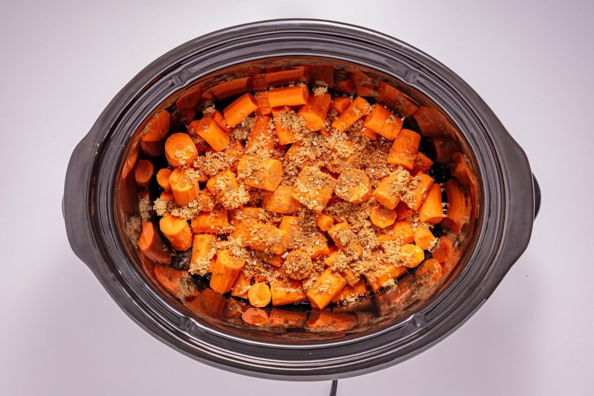 Chopped carrots with seasoning in a slow cooker, viewed from above.