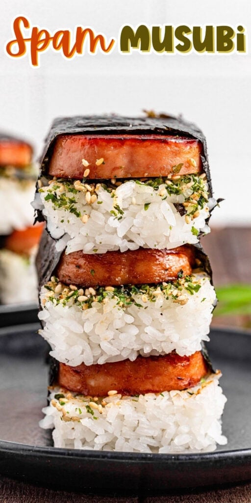 Three stacked Spam musubi on a black plate, with rice and nori seaweed wrapping.