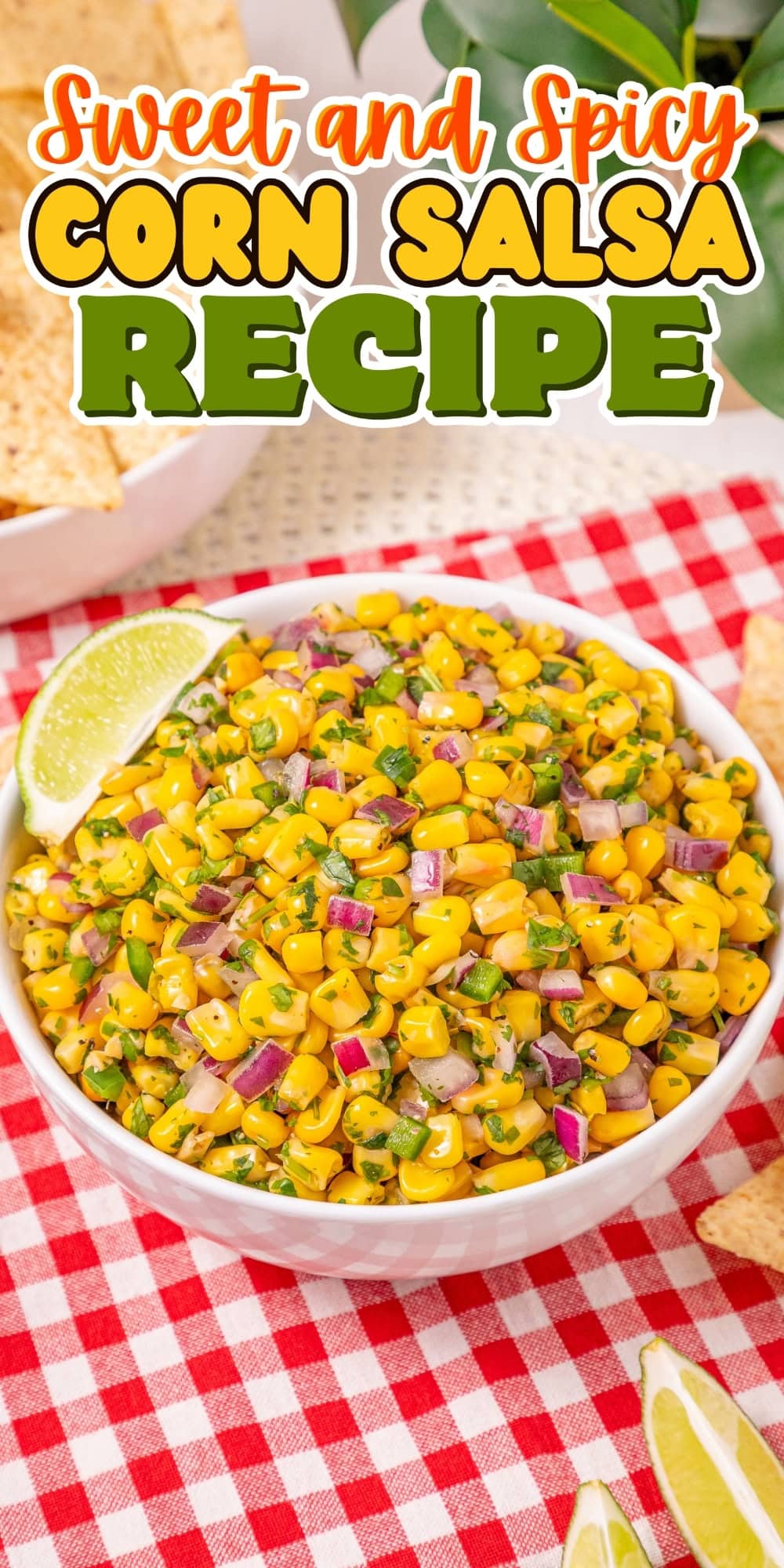 Bowl of corn salsa with red onion and lime on a red checkered tablecloth.