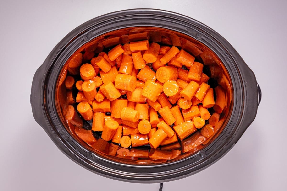Chopped carrots in a slow cooker seen from above.