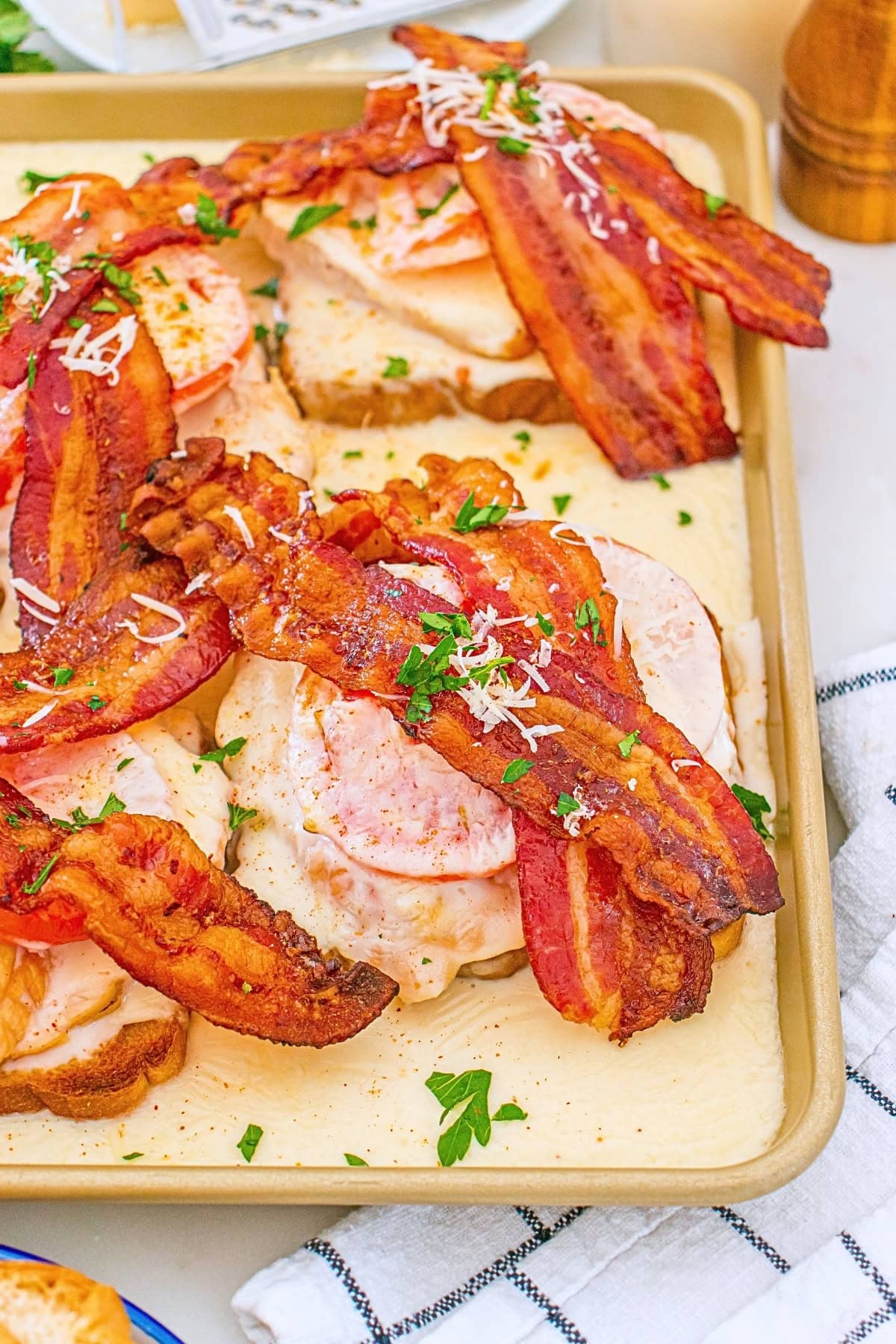Open-faced sandwiches with turkey, bacon, tomato, herbs, and shredded cheese.