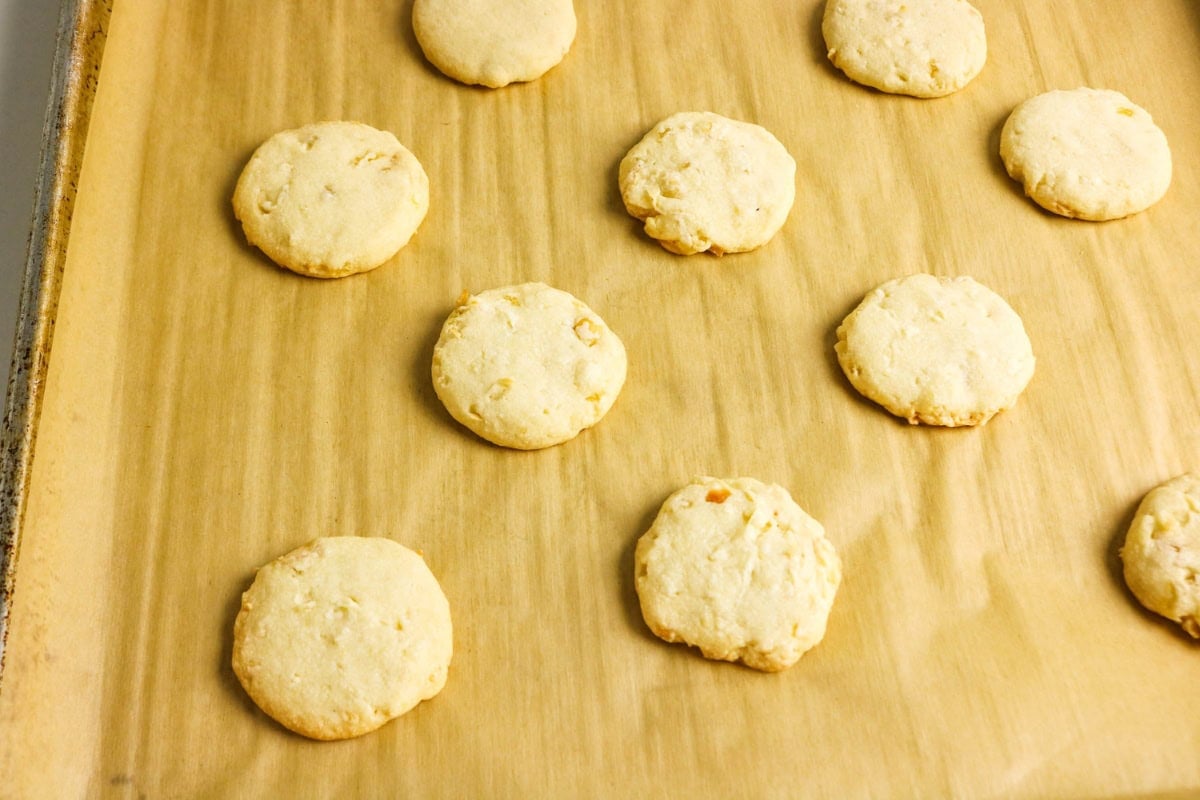 Nine round cookies on parchment paper on a baking sheet.