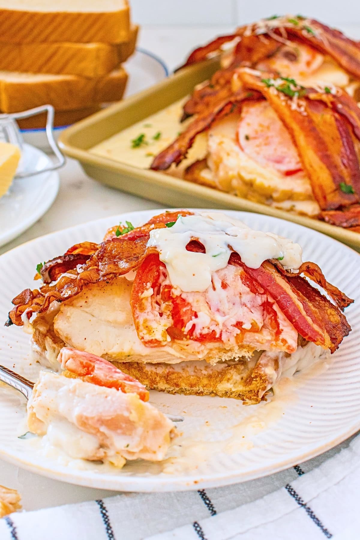 Open-faced sandwich with turkey, tomato, bacon, and creamy sauce on a plate.