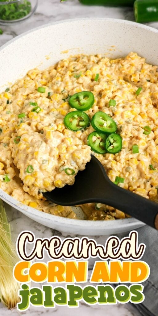 Creamed corn in a skillet, topped with sliced jalapenos and green onions.