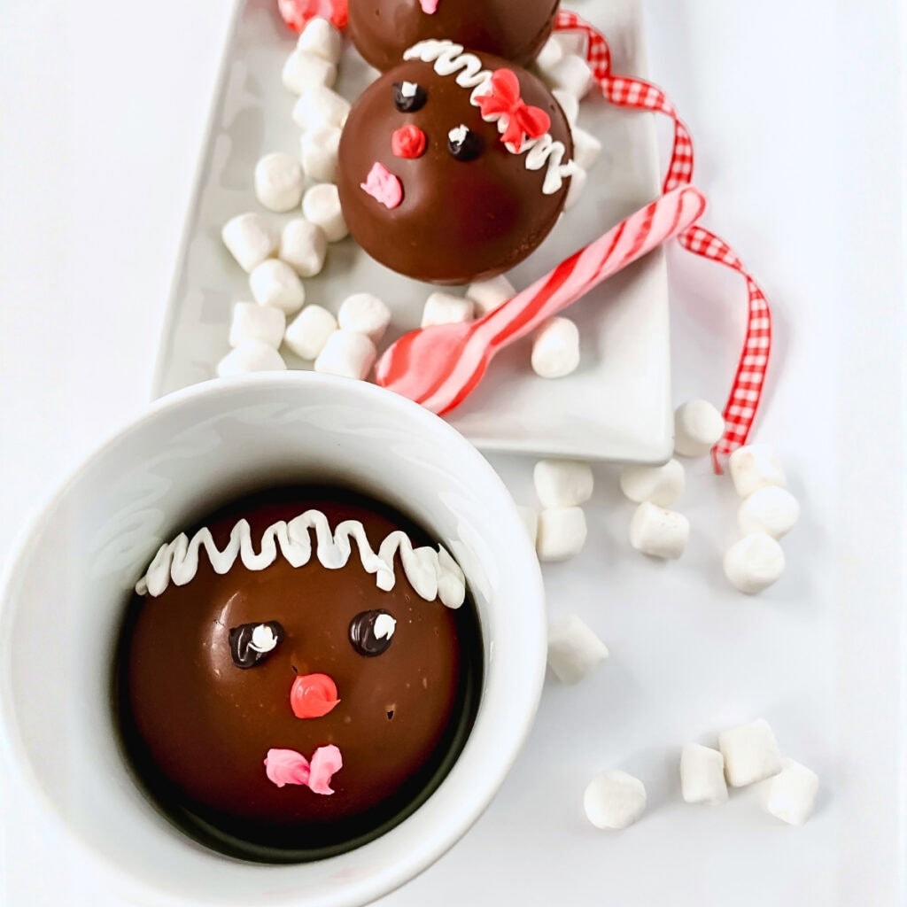 Chocolate spheres decorated as faces, surrounded by mini marshmallows.