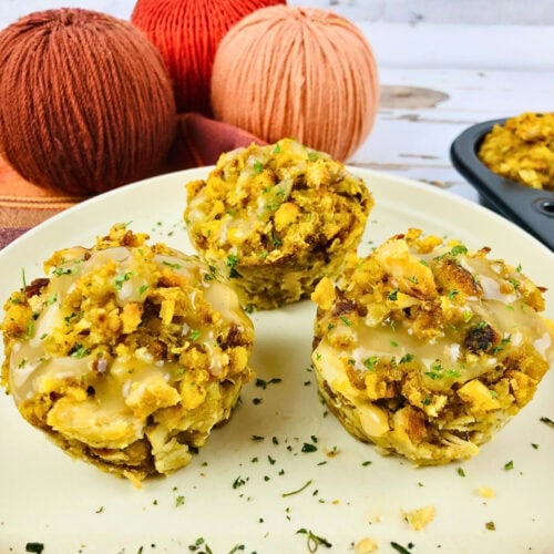 Three stuffing muffins with gravy on a plate, with yarn balls in the background.