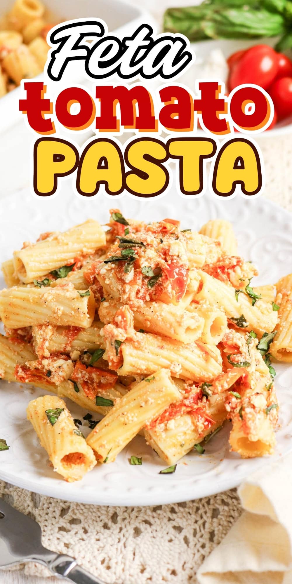 Rigatoni pasta with feta, tomatoes, and herbs on a white plate.