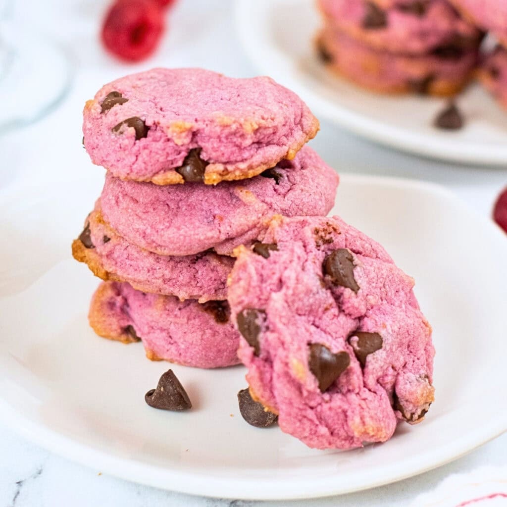 A stack of pink chocolate chip cookies on a white plate.