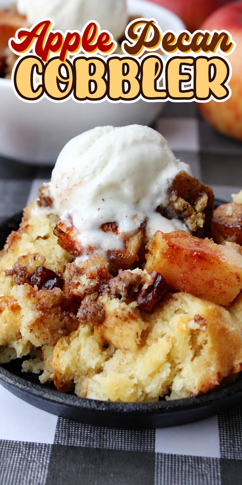 Apple pecan cobbler topped with vanilla ice cream on a black plate.