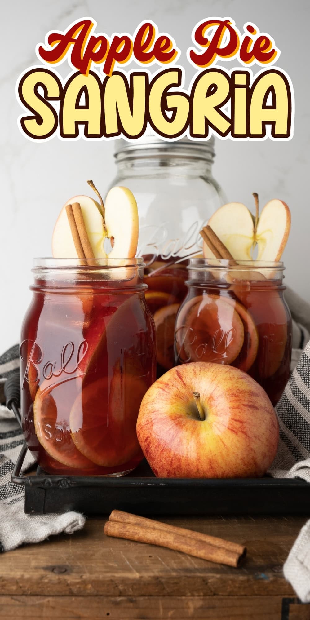 Mason jars of apple pie sangria with apple slices and cinnamon sticks.