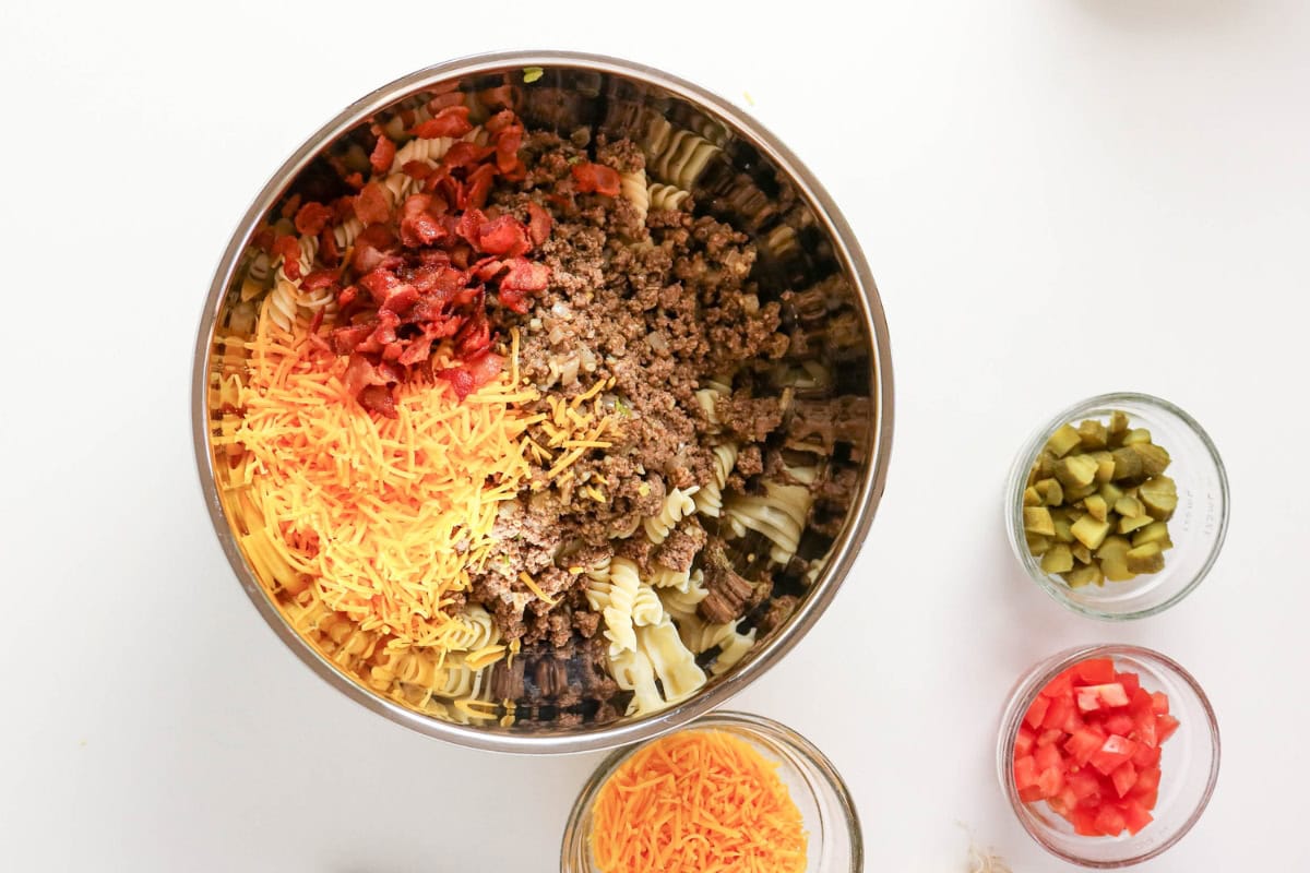 Mix pasta, ground beef, cheddar, tomatoes, and pickles in a large bowl.