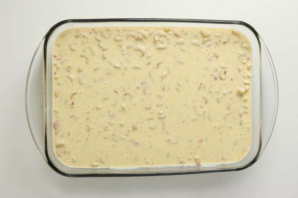 Unbaked macaroni and cheese mixture in a glass casserole dish.