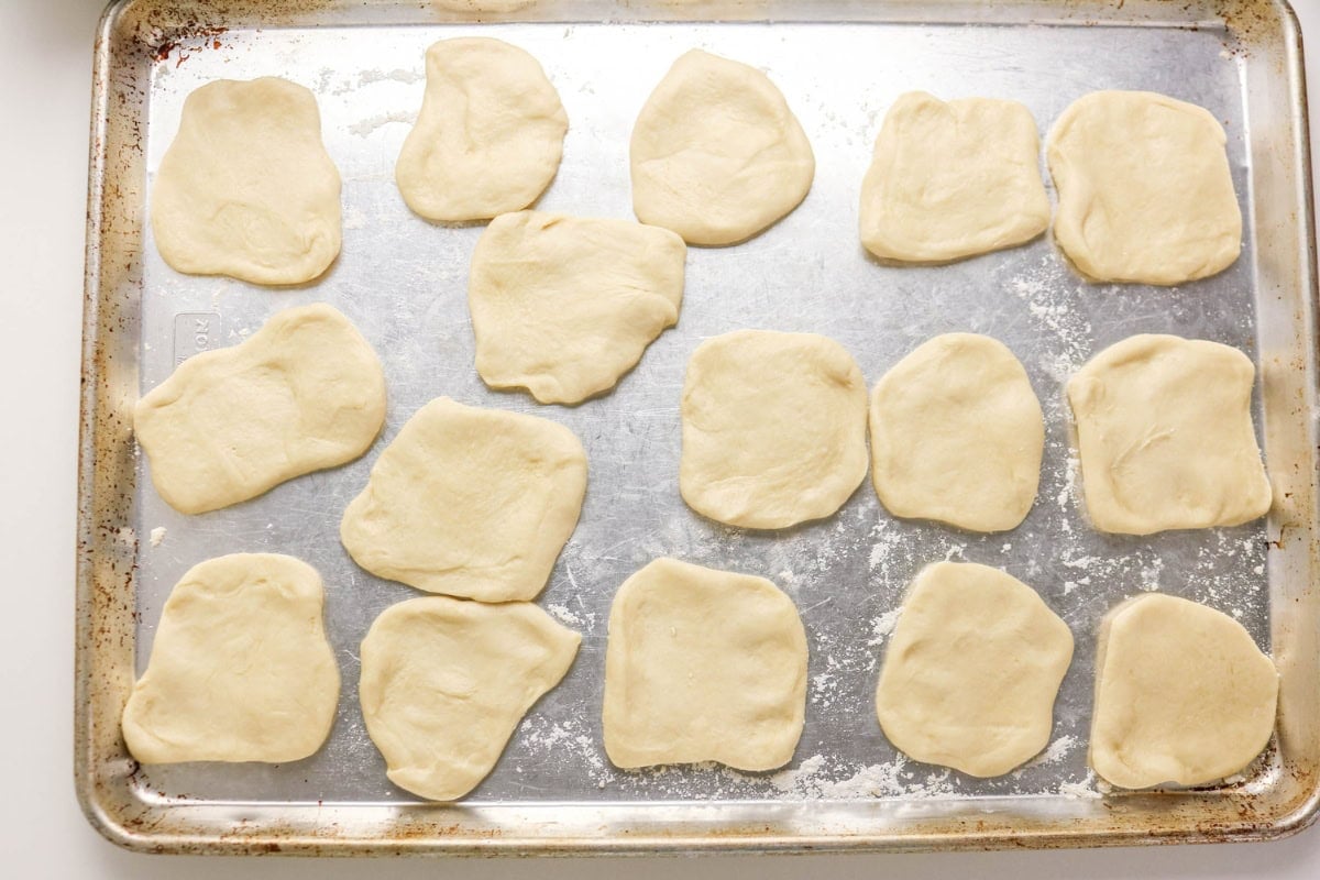 Raw dough pieces arranged on a metal baking sheet before baking.