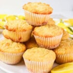 A plate of lemon muffins stacked with lemon slices in the background.