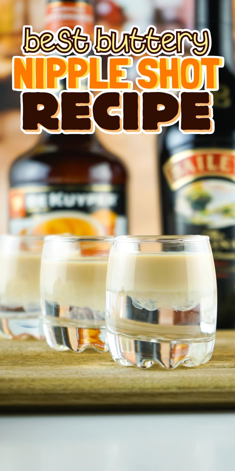 Three layered shots on a wooden board with liqueur bottles in the background.