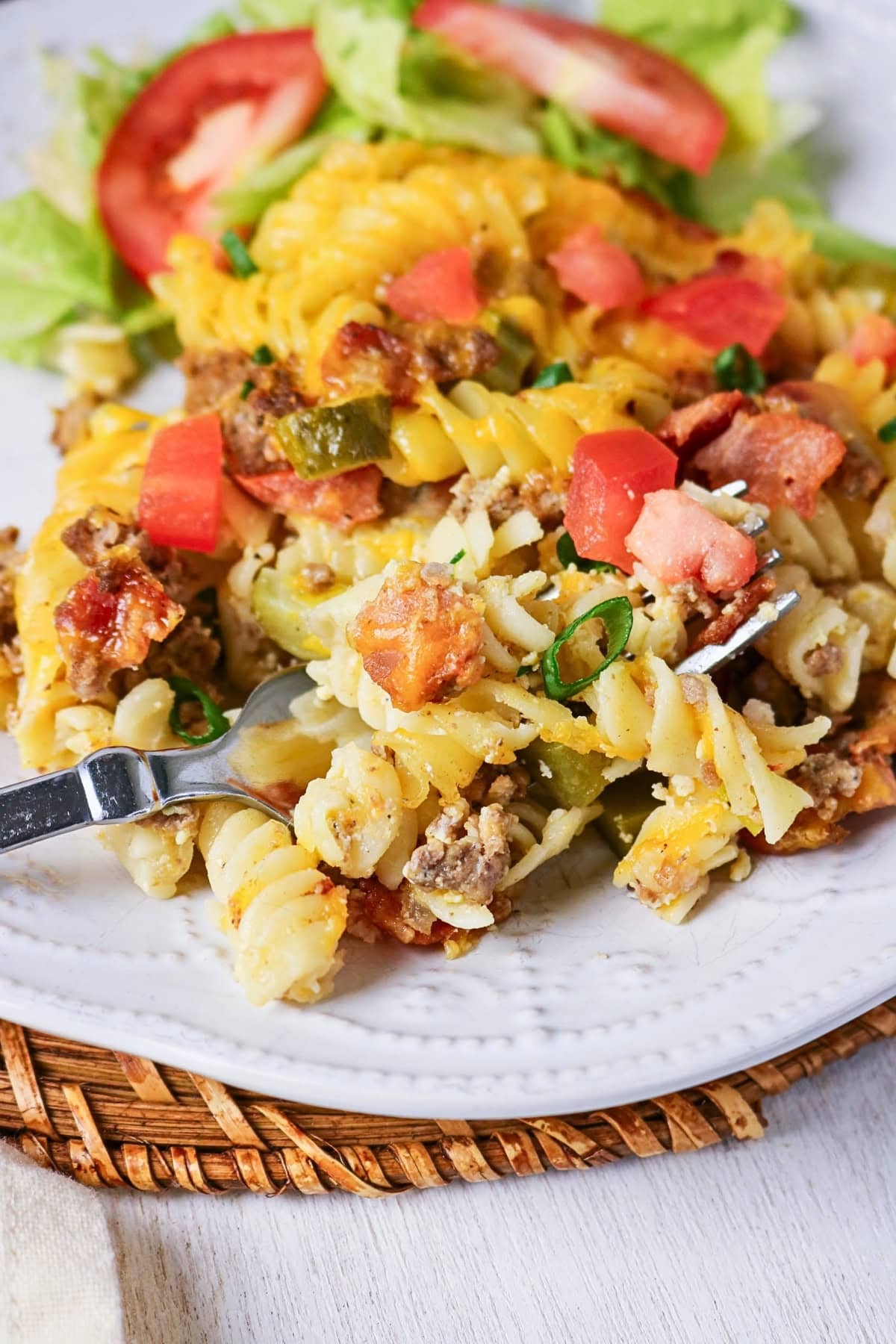 Rotini pasta casserole with ground meat, cheese, and diced tomatoes on a plate.