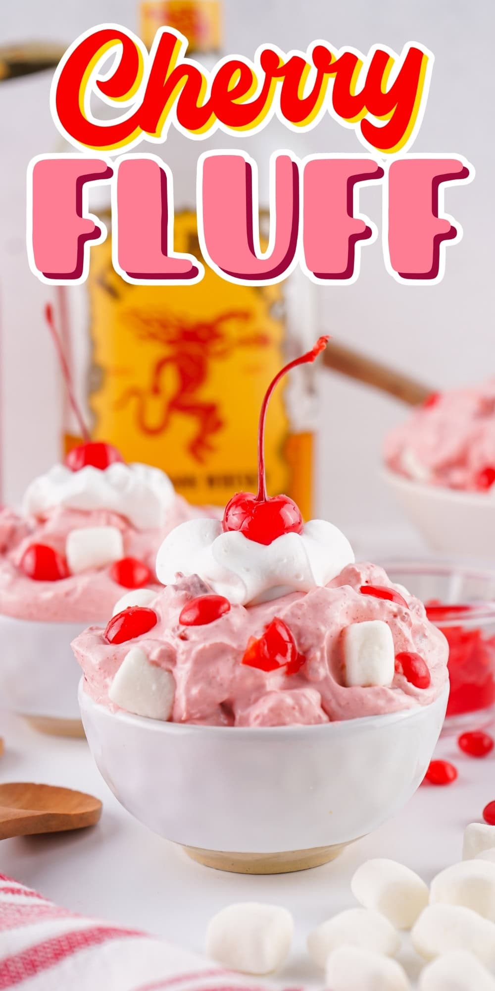Cherry fluff dessert in a bowl topped with marshmallows and a cherry.