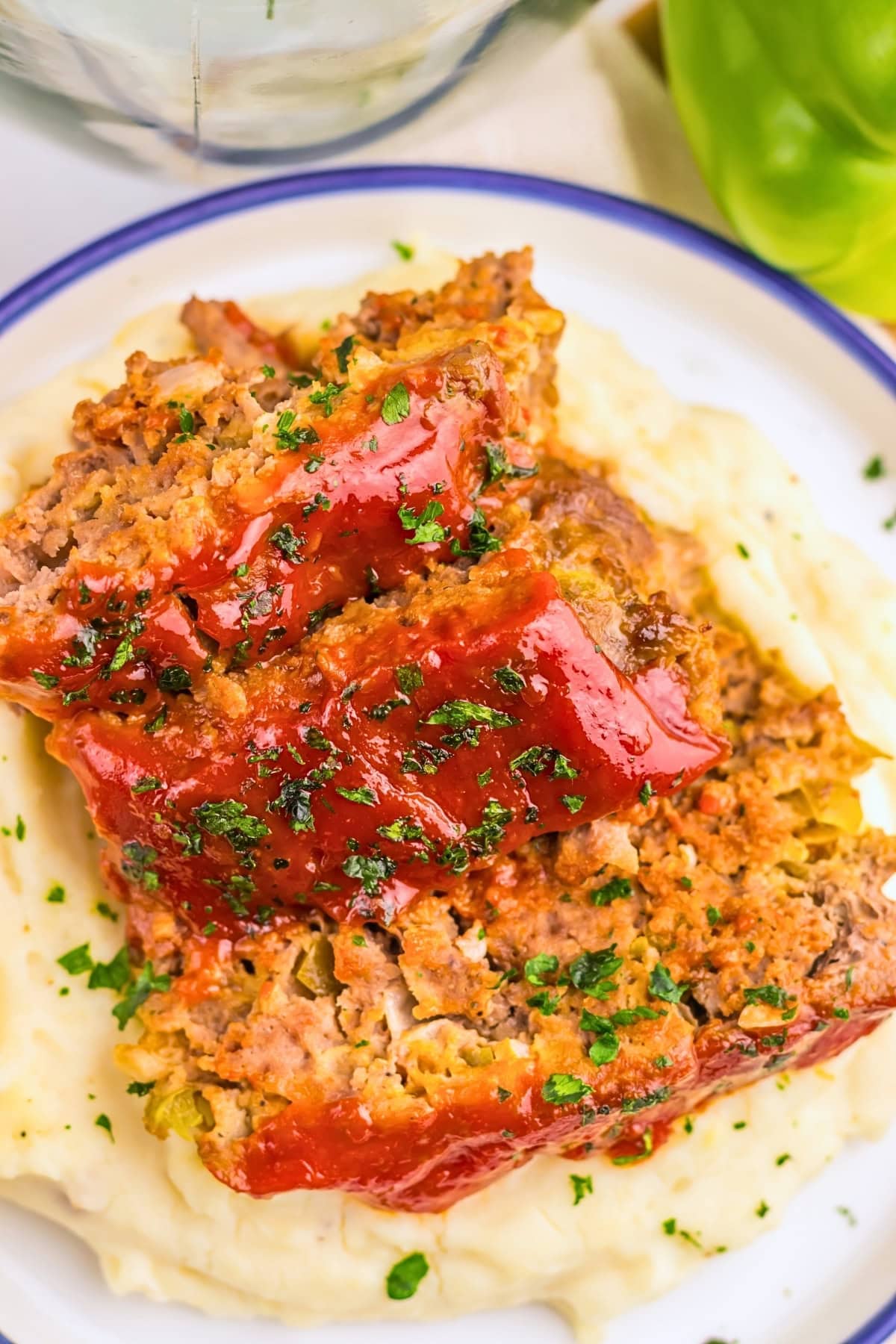 Meatloaf slices on mashed potatoes, topped with ketchup and parsley.
