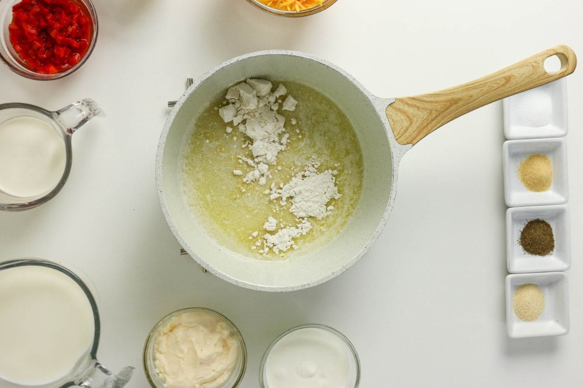 Melted butter, flour, milk, cheese, spices, and sauces in a pan.