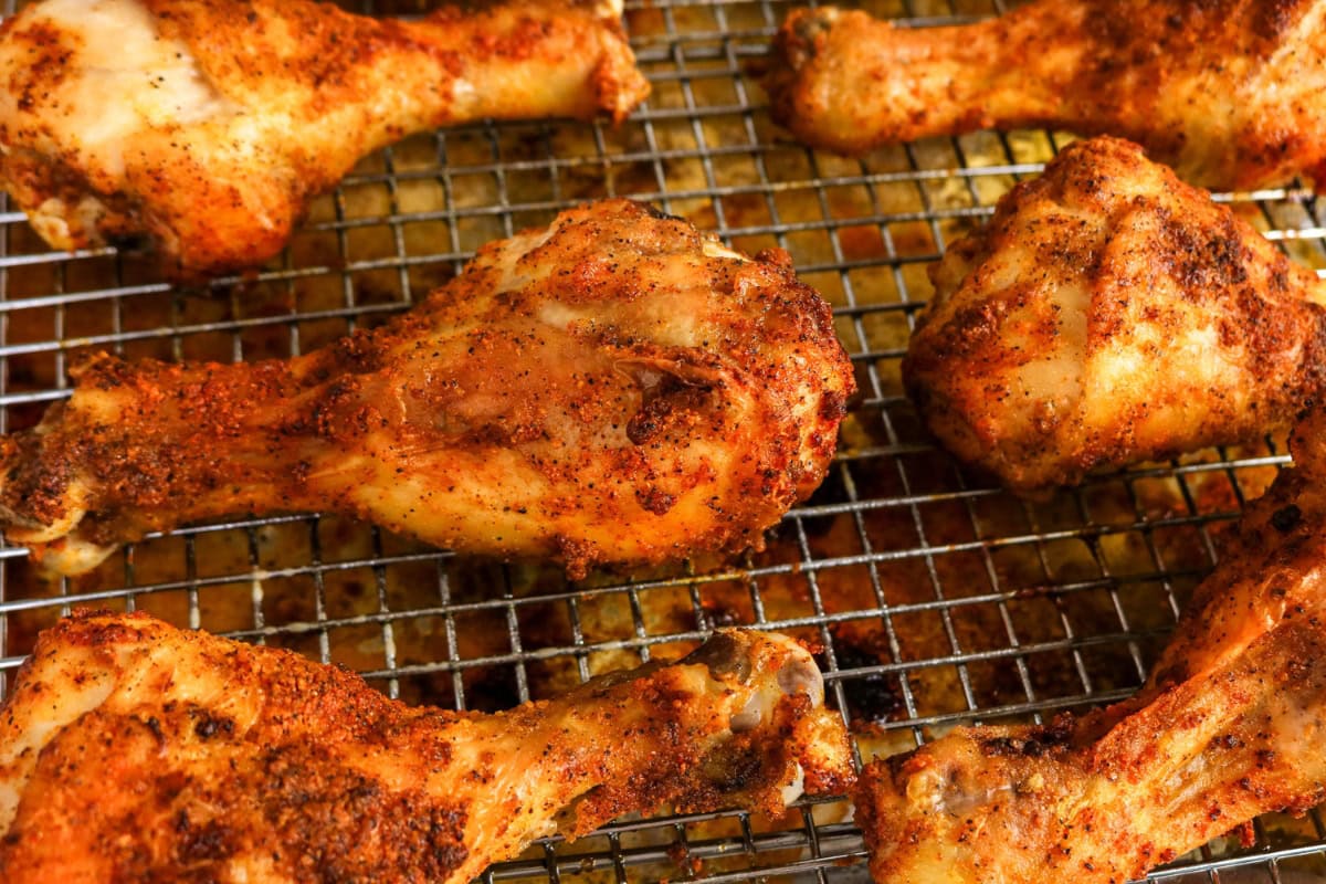Seasoned baked chicken drumsticks on a metal cooling rack.