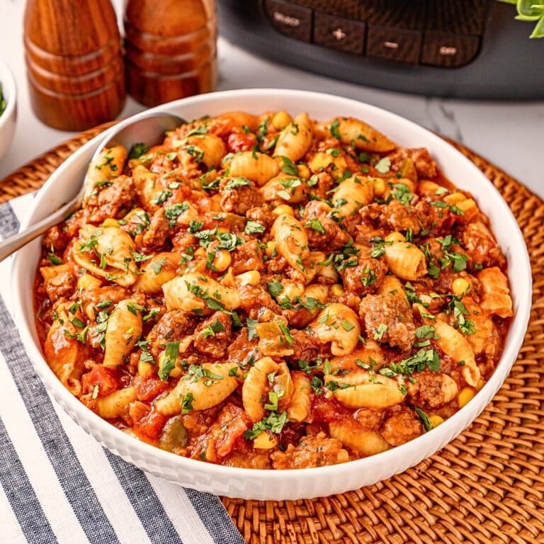 Pasta with tomato sauce, ground meat, corn, and herbs in a white bowl.