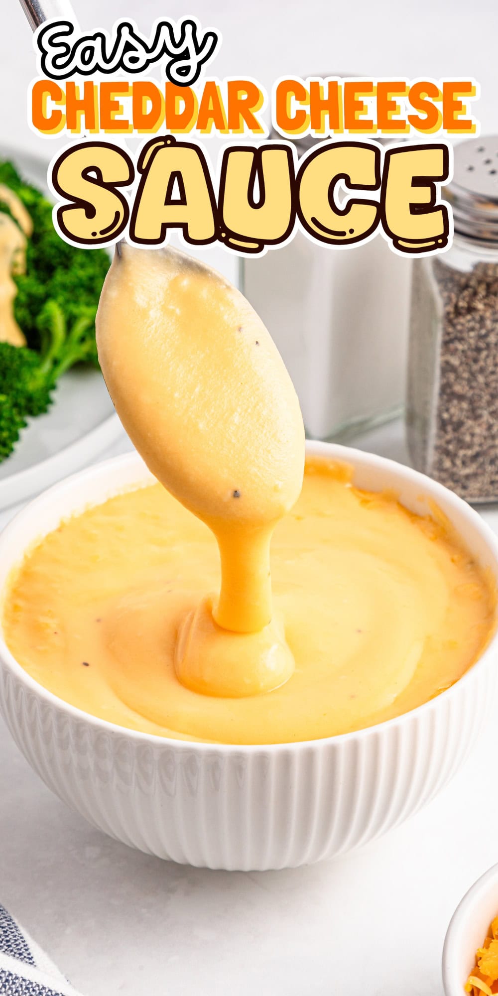 Spoon dipped in a bowl of creamy cheddar cheese sauce.
