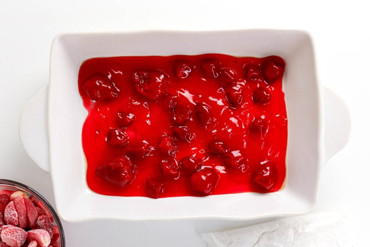 White dish with bright red cherry pie filling spread across the bottom.